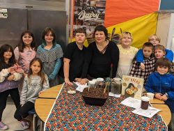 group photo of teacher and students standing in front of a table